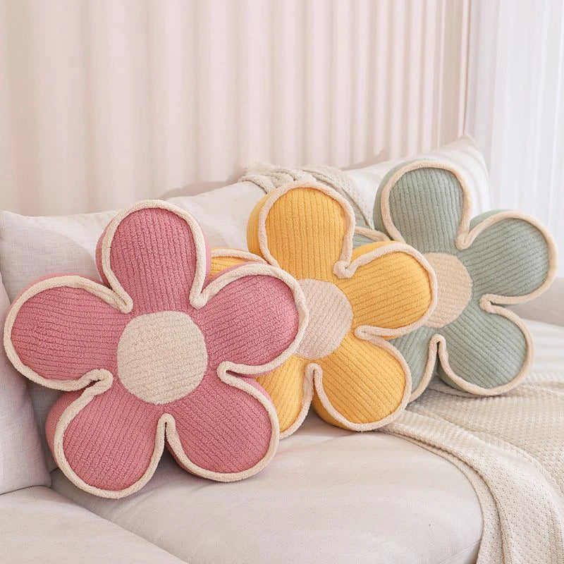 three thick flower cushions, pink, yellow, and green on a couch