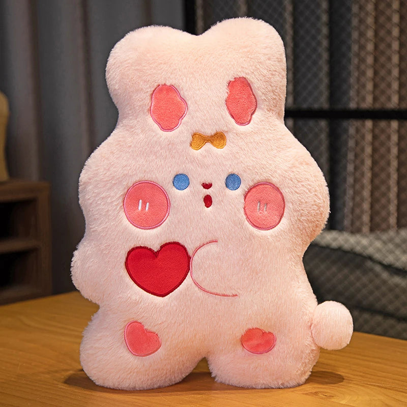 a sweet, candy shaped pink bunny cushion with rosy strawberry love heart cheeks, a bow in its hair, and holding a love heart