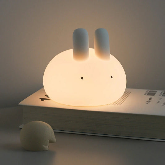 a white silicone cartoon bunny night light on a bedside locker