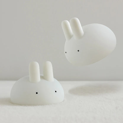 two white silicone cartoon bunny night lights on a blanket