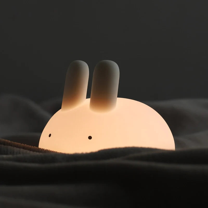 a white silicone cartoon bunny night light on a blanket