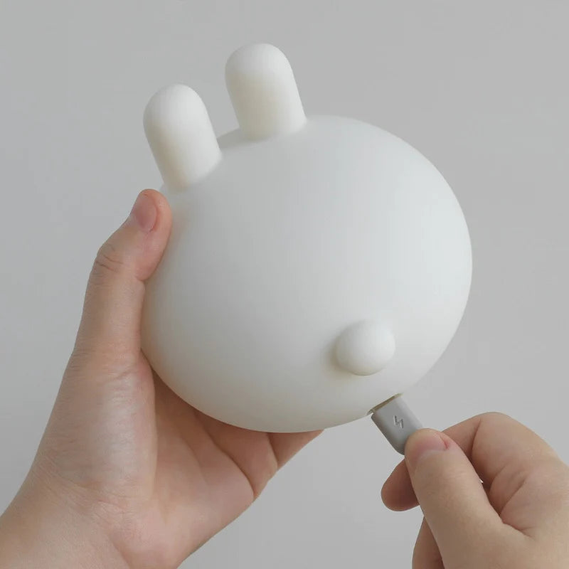 a white silicone cartoon bunny night light being charged