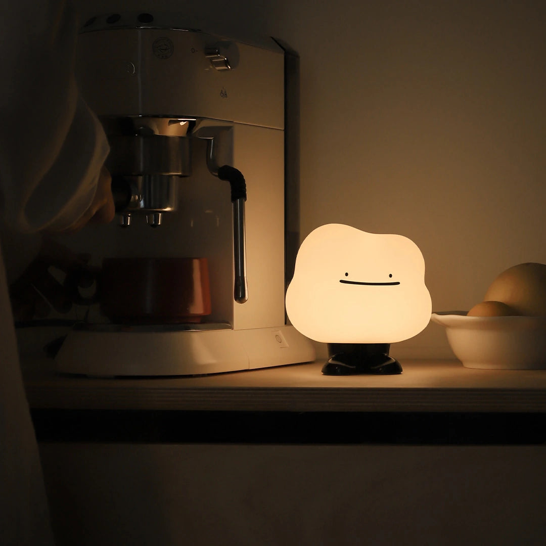 a white silicone cartoon cloud night light on a bedside locker