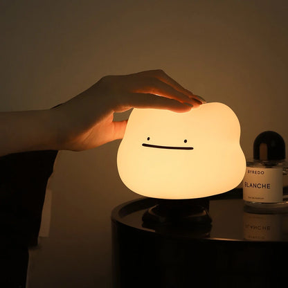 a white silicone cartoon cloud night light on a bedside locker