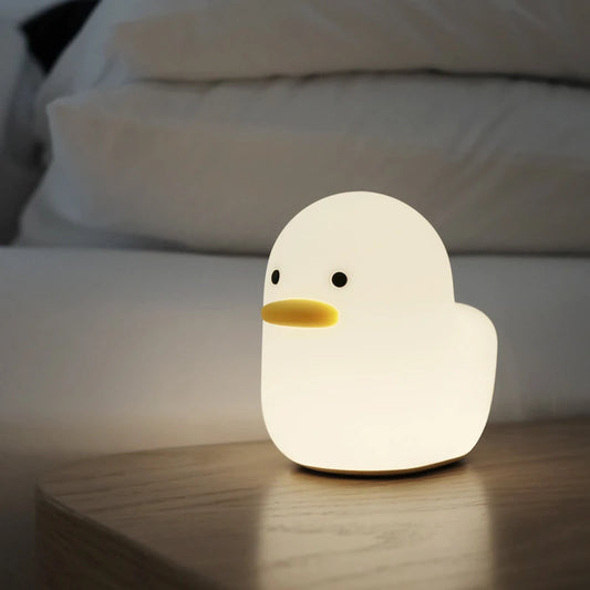 a white silicone cartoon duck night light on a bedside locker