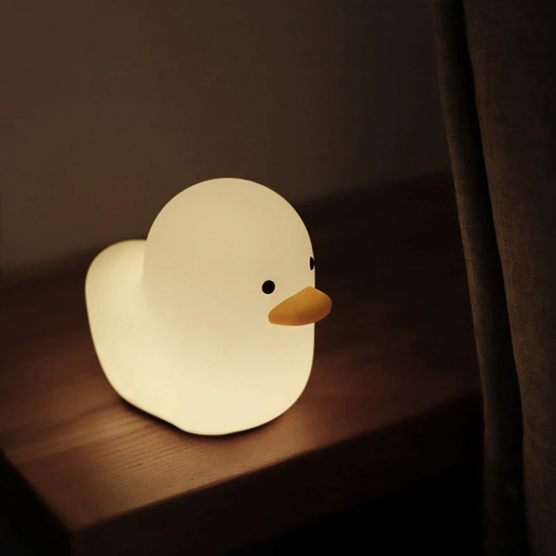 a white silicone cartoon duck night light on a bedside locker