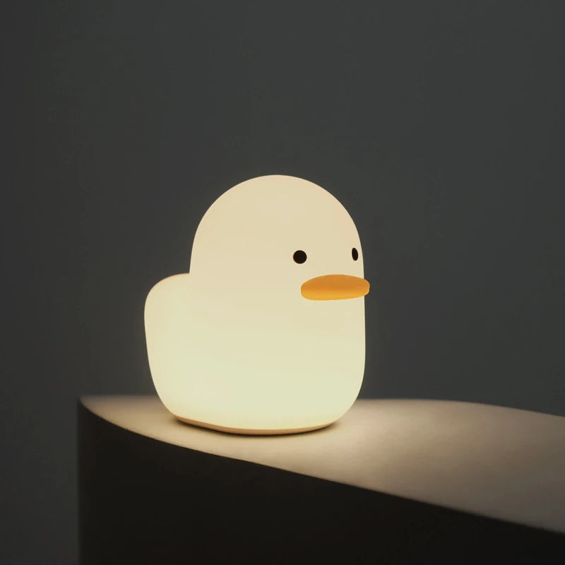 a white silicone cartoon duck night light on a bedside locker