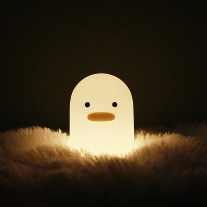 a white silicone cartoon duck night light on a blanket