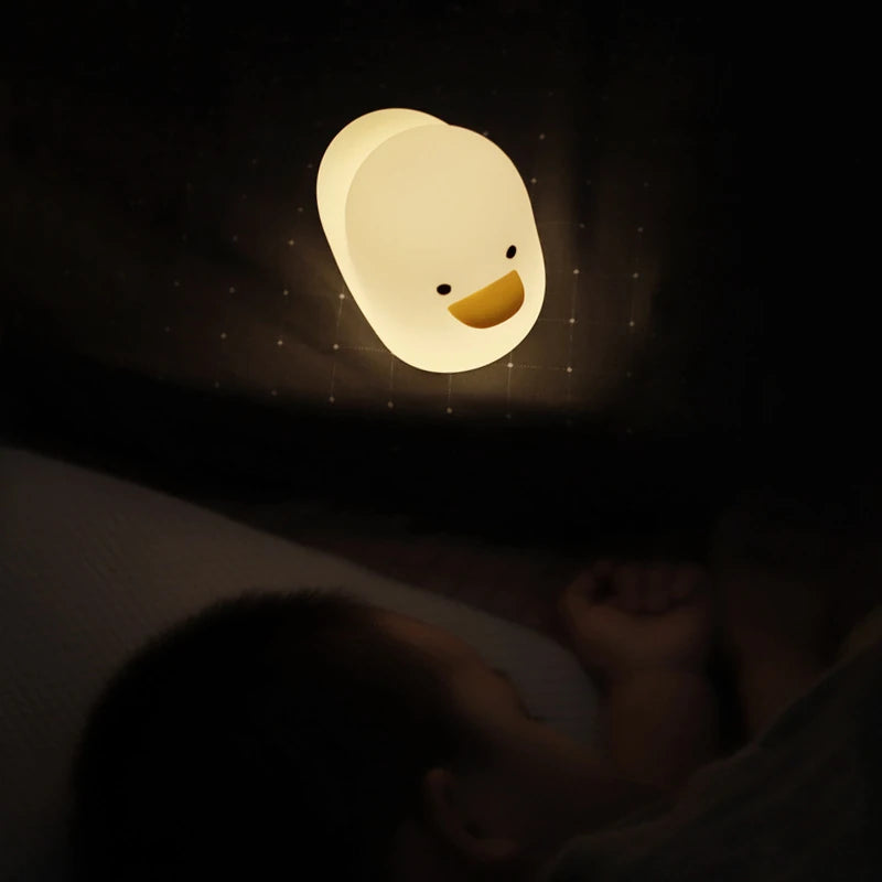 a white silicone cartoon duck night light on a bedside locker