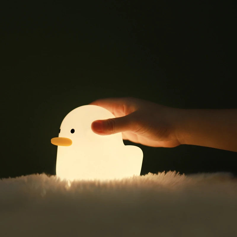 a white silicone cartoon duck night light on a blanket