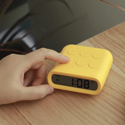 a yellow minimalist digital alarm clock on a bedside locker