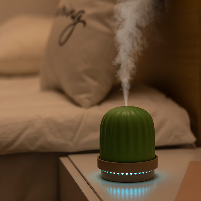 a small green cactus humidifier and night light releasing vapour and emitting a dim light