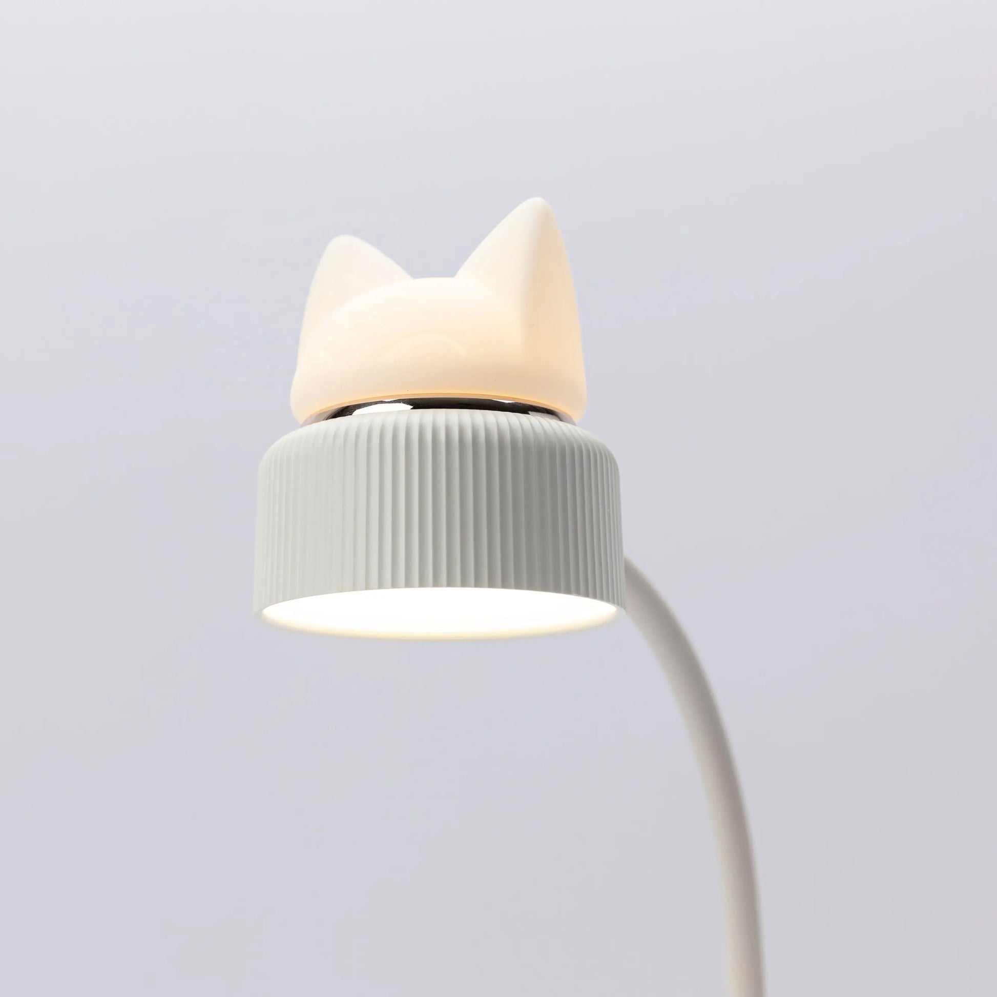 a closeup of a desk lamp showing its directional light and silicone kitten ear night light both turned on