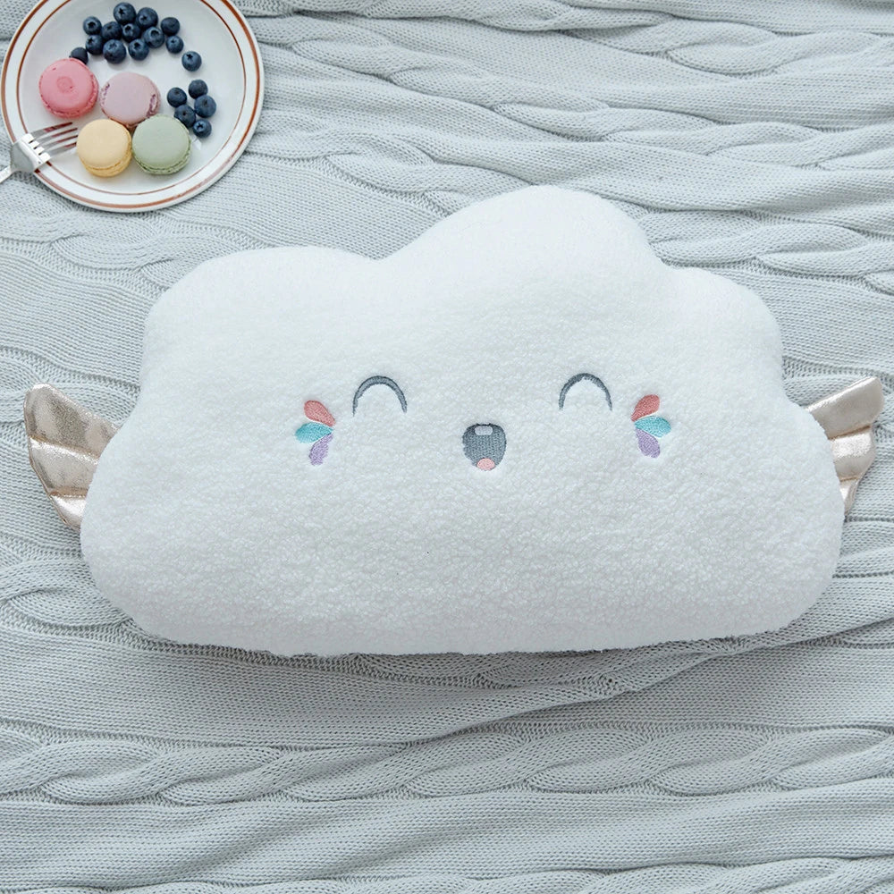 a white cloud cushion with golden wings and pastel eyes and mouths on a bed