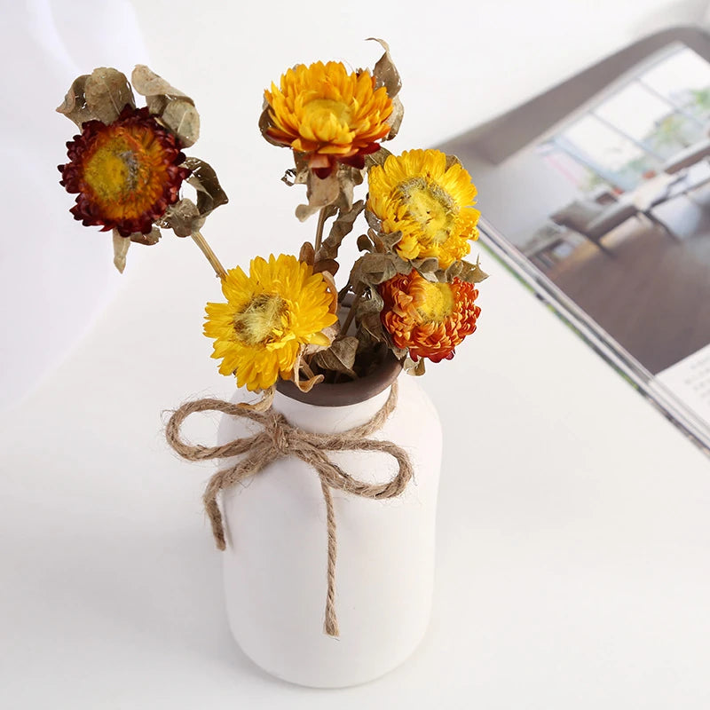 a small rustic matte white ceramic flower vase shaped like a bordeaux wine bottle with a twine bow around its neck