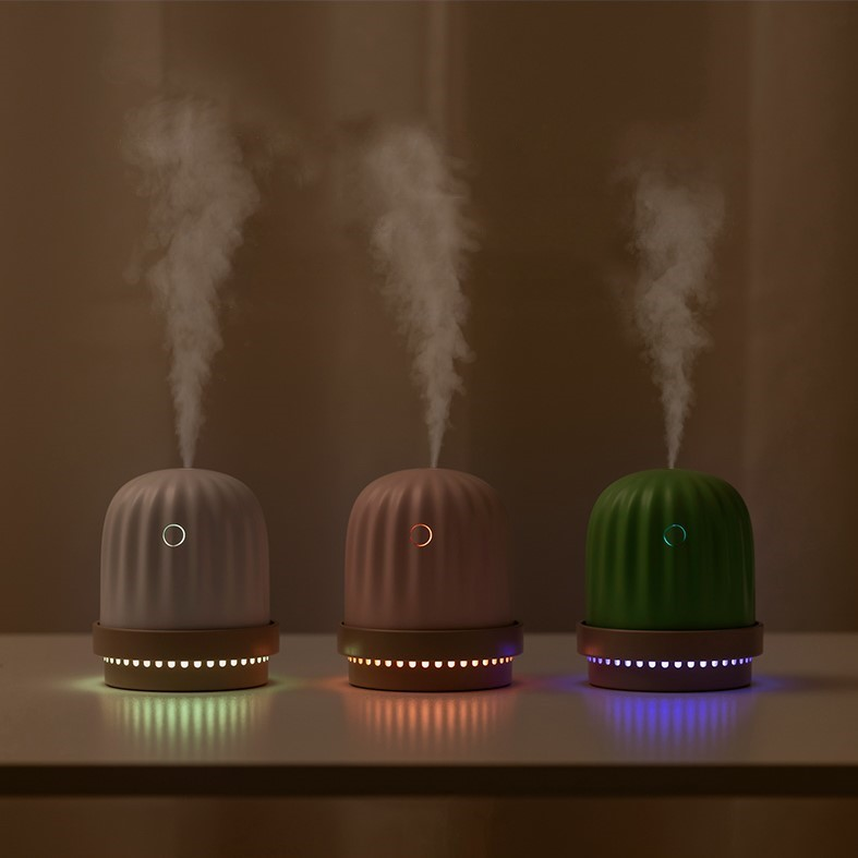 small white, pink, and green cactus humidifiers and night lights releasing vapour and emitting dim light