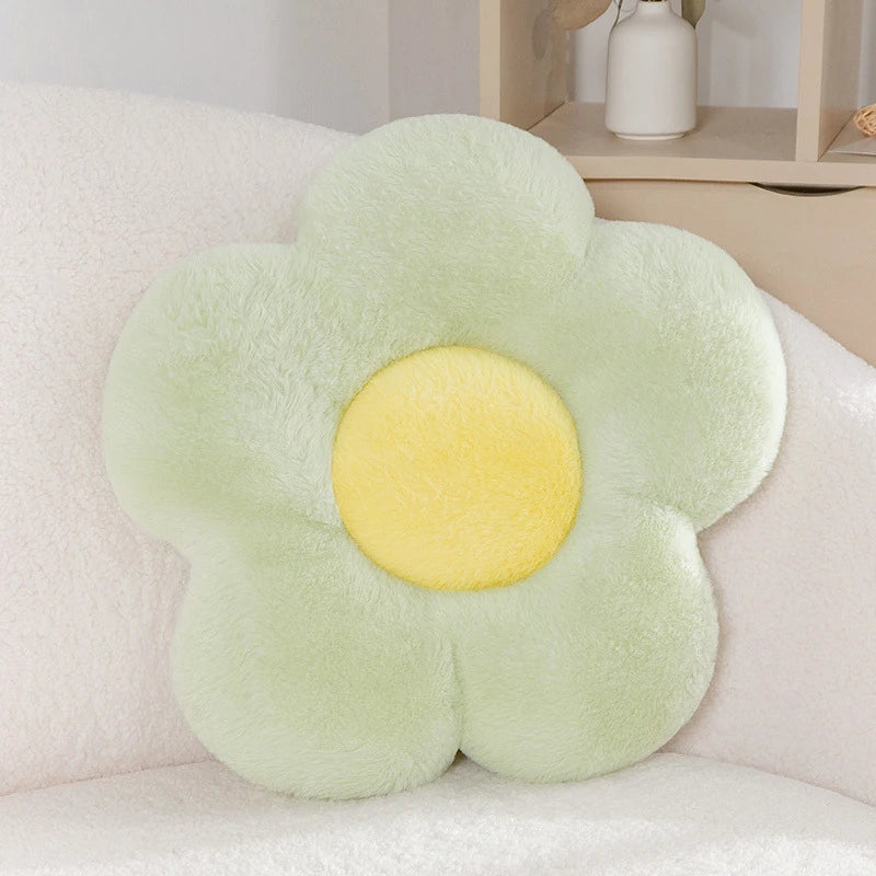 a pastel daisy cushion with green petals and a yellow centre on a couch