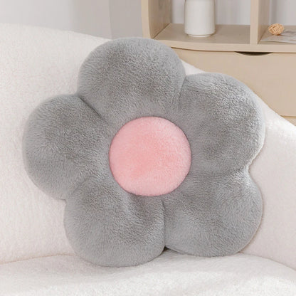 a pastel daisy cushion with grey petals and a pink centre on a couch