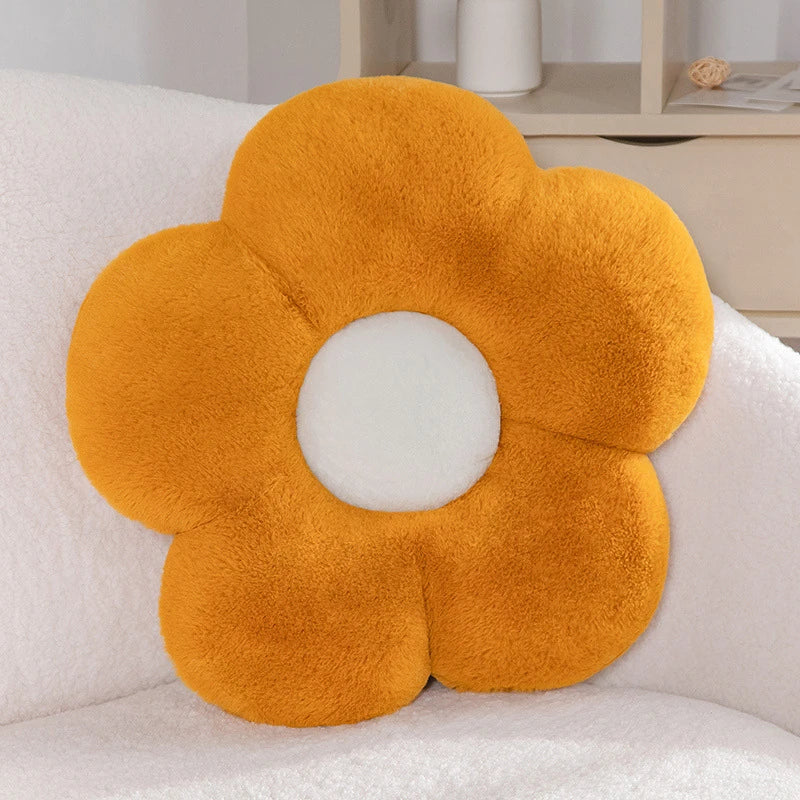 a pastel daisy cushion with orange petals and a white centre on a couch