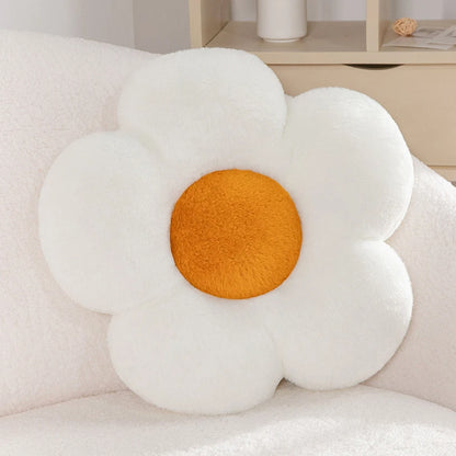 a pastel daisy cushion with white petals and an orange centre on a couch