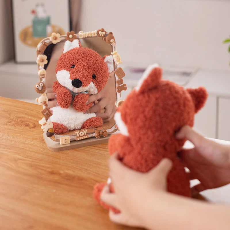 a red fox soft toy wearing a light blue bow tie in front of a mirror