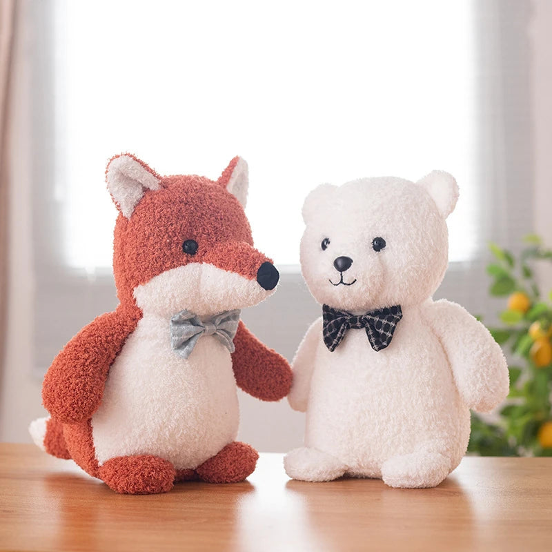 a red fox soft toy wearing a light blue bow tie and a white polar bear soft toy wearing a black bow tie