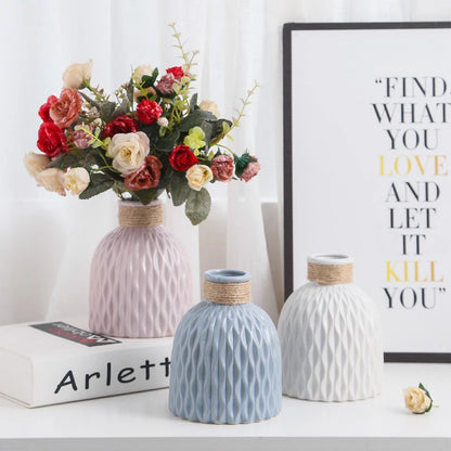 three pink, blue, and white vases with ripple textures and necks wound with yarn, shaped like fiasco wine bottles