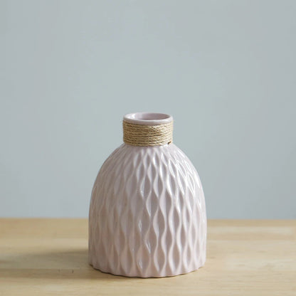 a pink vase with a ripple texture and a neck wound with yarn, shaped like a fiasco wine bottle