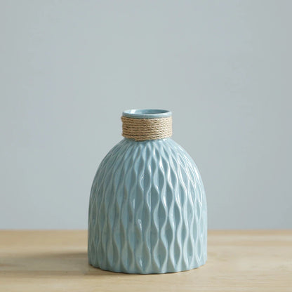 a blue vase with a ripple texture and a neck wound with yarn, shaped like a fiasco wine bottle