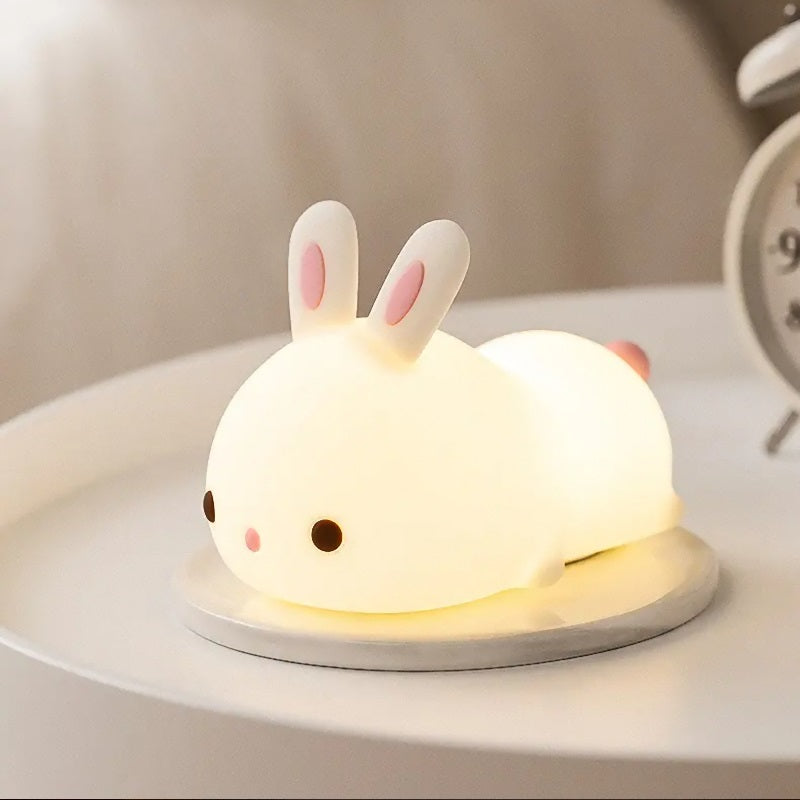 a white silicone cartoon bunny night light on a bedside locker