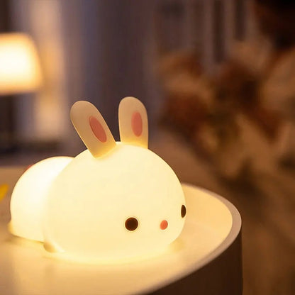 a white silicone cartoon bunny night light on a bedside locker