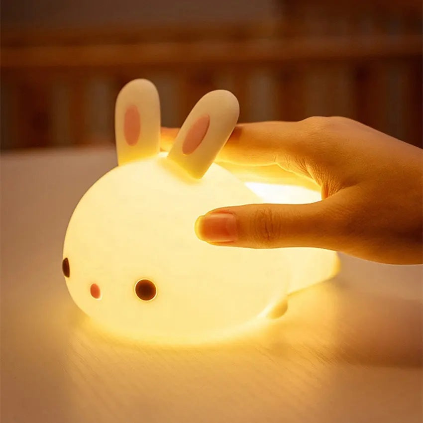 a white silicone cartoon bunny night light on a bedside locker