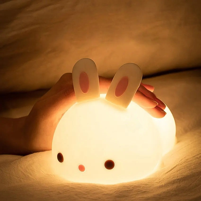 a white silicone cartoon bunny night light on a bedside locker