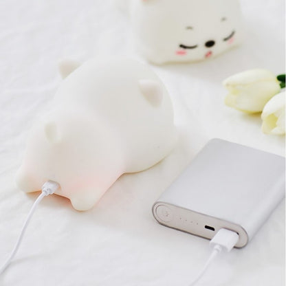 a white silicone cartoon cat night light on a blanket being charged